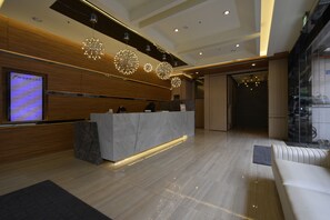 A modern reception area with a marble counter, wooden paneling, and decorative lighting fixtures. - FM Hotel (Taichung)