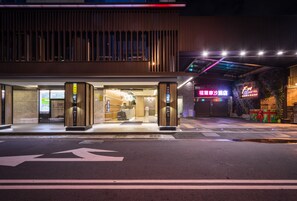 A modern hotel entrance with a glass facade, a reception desk, and a neon sign. - FM Hotel (Taichung)