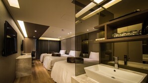 Une chambre d’hôtel moderne avec un grand lit, un bureau et une salle de bain dotée d’un grand miroir et d’un lavabo.