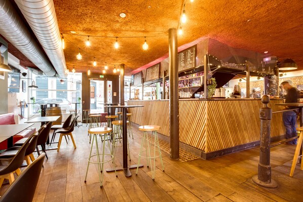 A restaurant interior with wooden floors, high stools, and a bar area. - The People Lille (Lille)