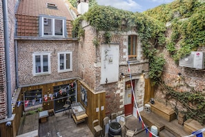 A courtyard with a wooden deck, brick buildings, and a flag.