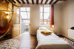 A bedroom with a bed, a window, a door leading to a balcony, and a lamp.