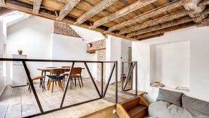 Un interior moderno con vigas de madera a la vista, un comedor con sillas y una mesa, y un sofá gris.