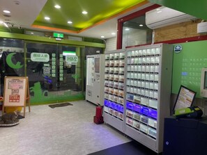 Una máquina expendedora con varios compartimentos, un extintor y una pantalla digital.