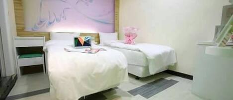 A hotel room with two beds, a large abstract painting on the wall, and a small table with a vase of flowers.