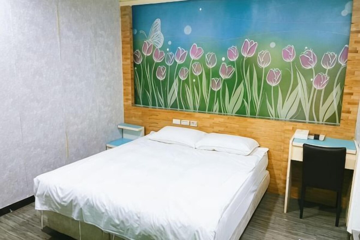 Una habitación de hotel con una cama, un escritorio, una silla y un cuadro en la pared.