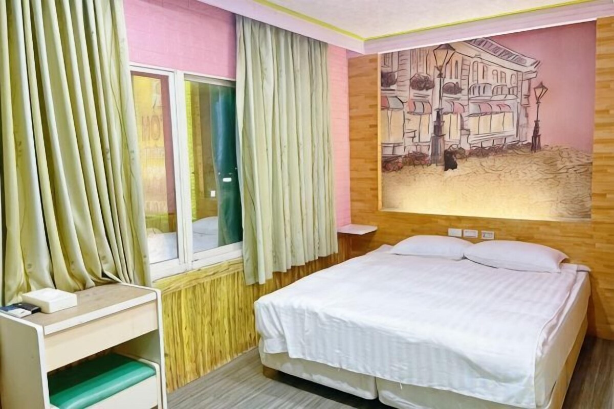 Una habitación de hotel con una cama, una mesita de noche, una ventana con cortinas y un mural en la pared.
