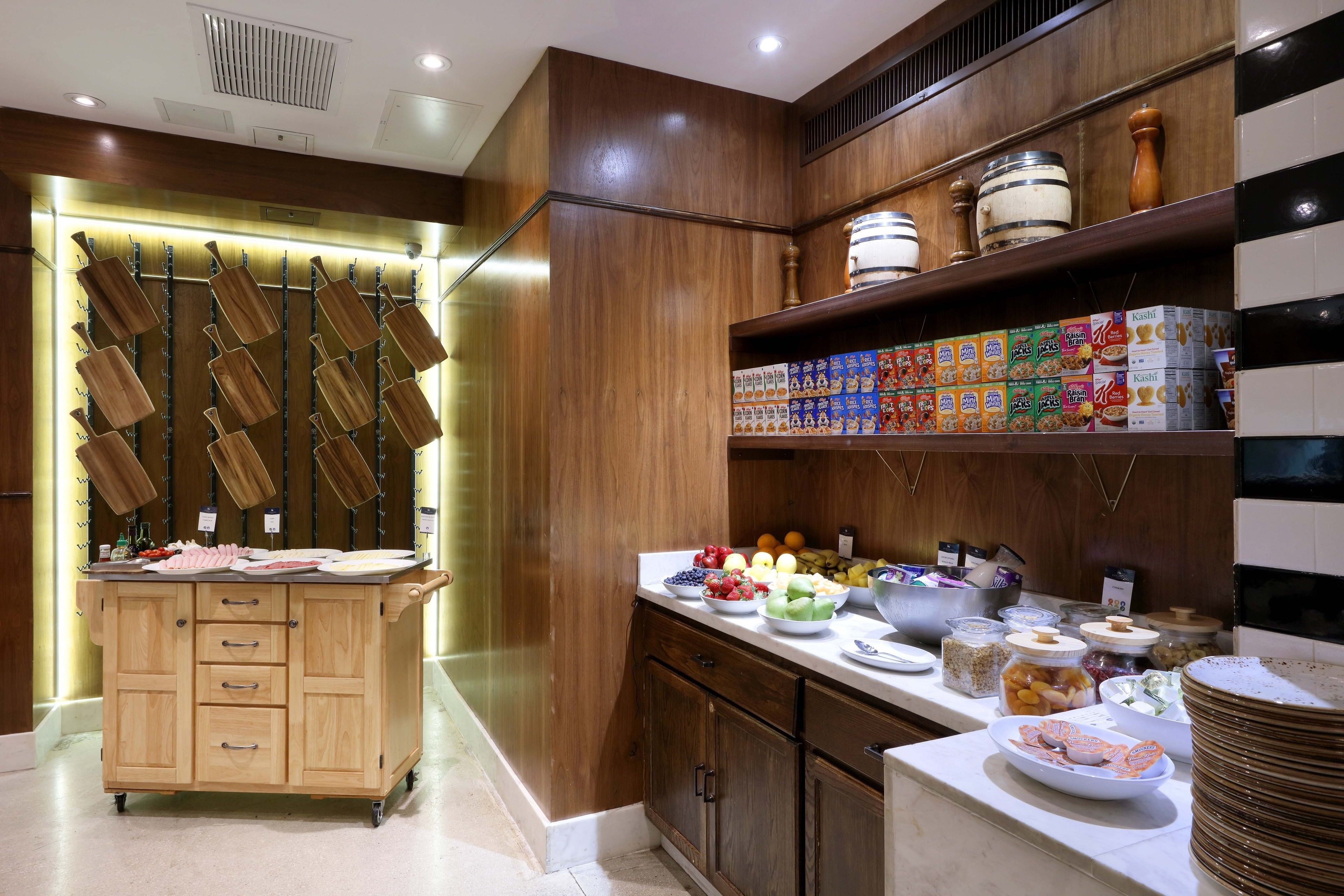 A kitchen area with wooden cabinets, a fruit bowl, and various food items on the counter.