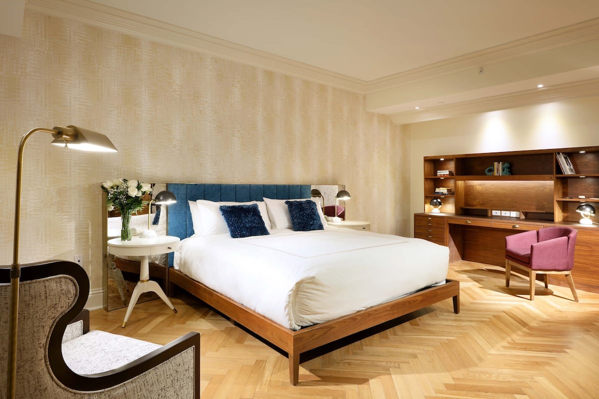 A modern bedroom with a large bed, bedside tables, a desk, and a chair.