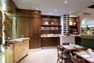 A restaurant with wooden cabinets, a counter with food items, and a seating area with tables and chairs.
