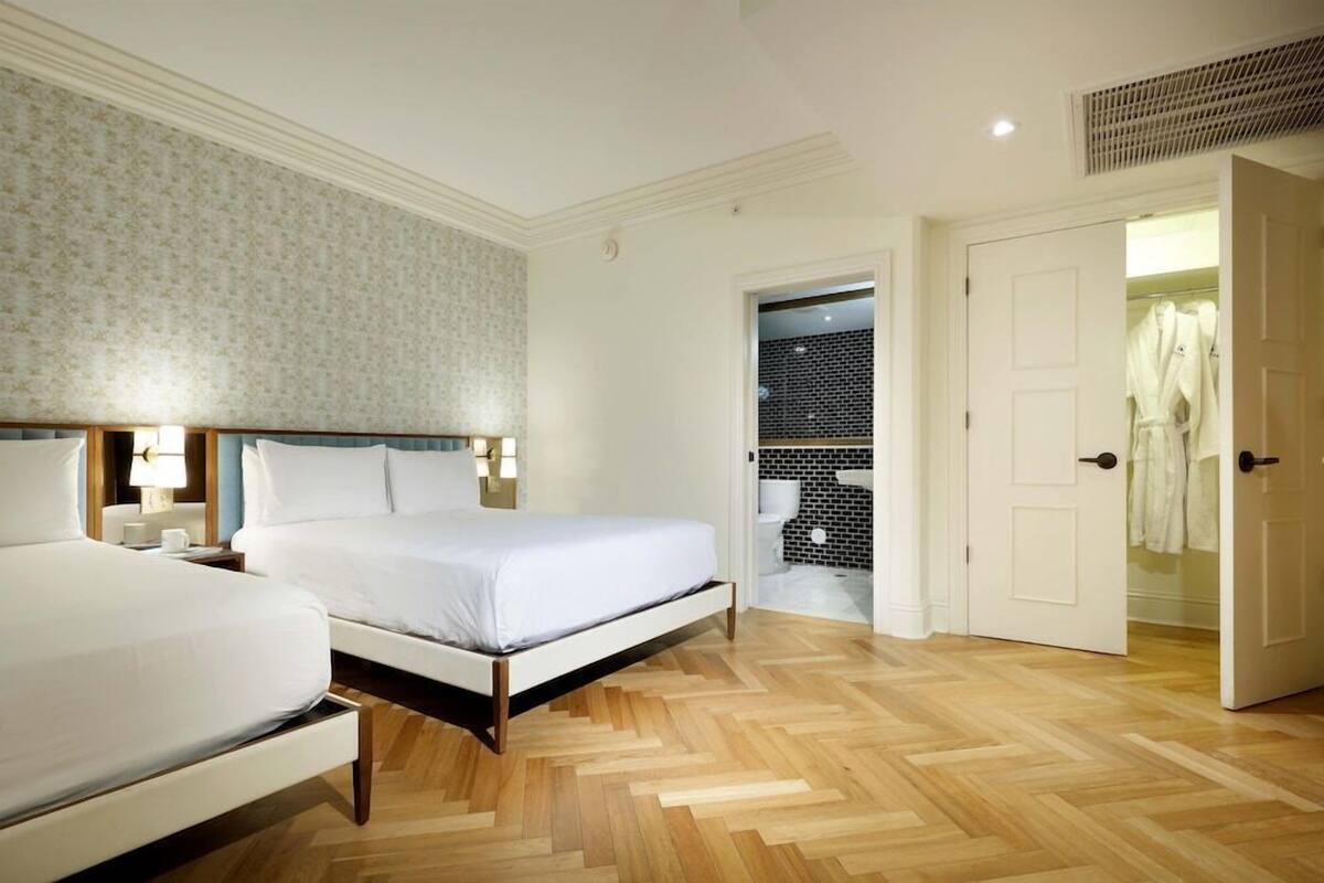 A hotel room with a bed, bedside tables, a wardrobe, and a bathroom visible through an open door.