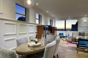 Un salon moderne avec un coin repas, de grandes fenêtres et une vue sur la ville.