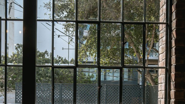 A room with large windows, a polished floor, and a view of a building and trees outside. - The Lot Boutique (Lima)