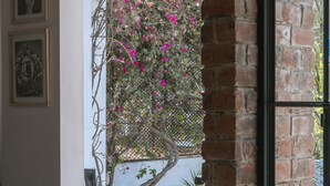 A doorway with a sign reading "SALIDA," a brick wall, a metal gate, and a tree with pink flowers. - The Lot Boutique (Lima)
