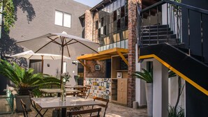 An outdoor patio with tables and chairs, a staircase, and potted plants. - The Lot Boutique (Lima)