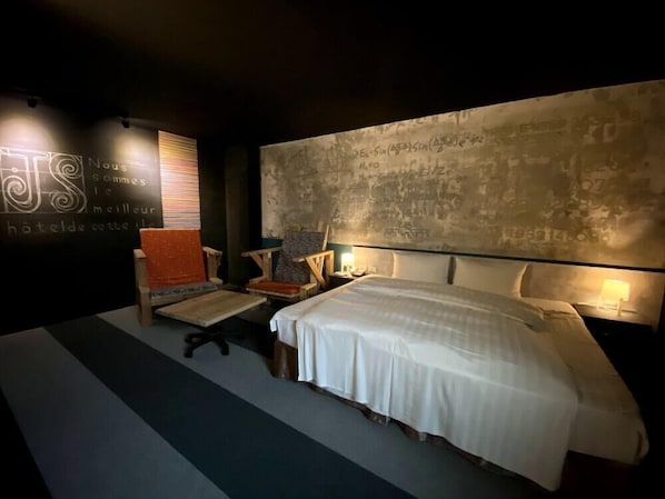 A modern bedroom with a large bed, a desk, and a chair. There is a wall with mathematical equations and a sign in French. - JS Hotel-Gallery Hotel-Zhongli (Taoyuan City)