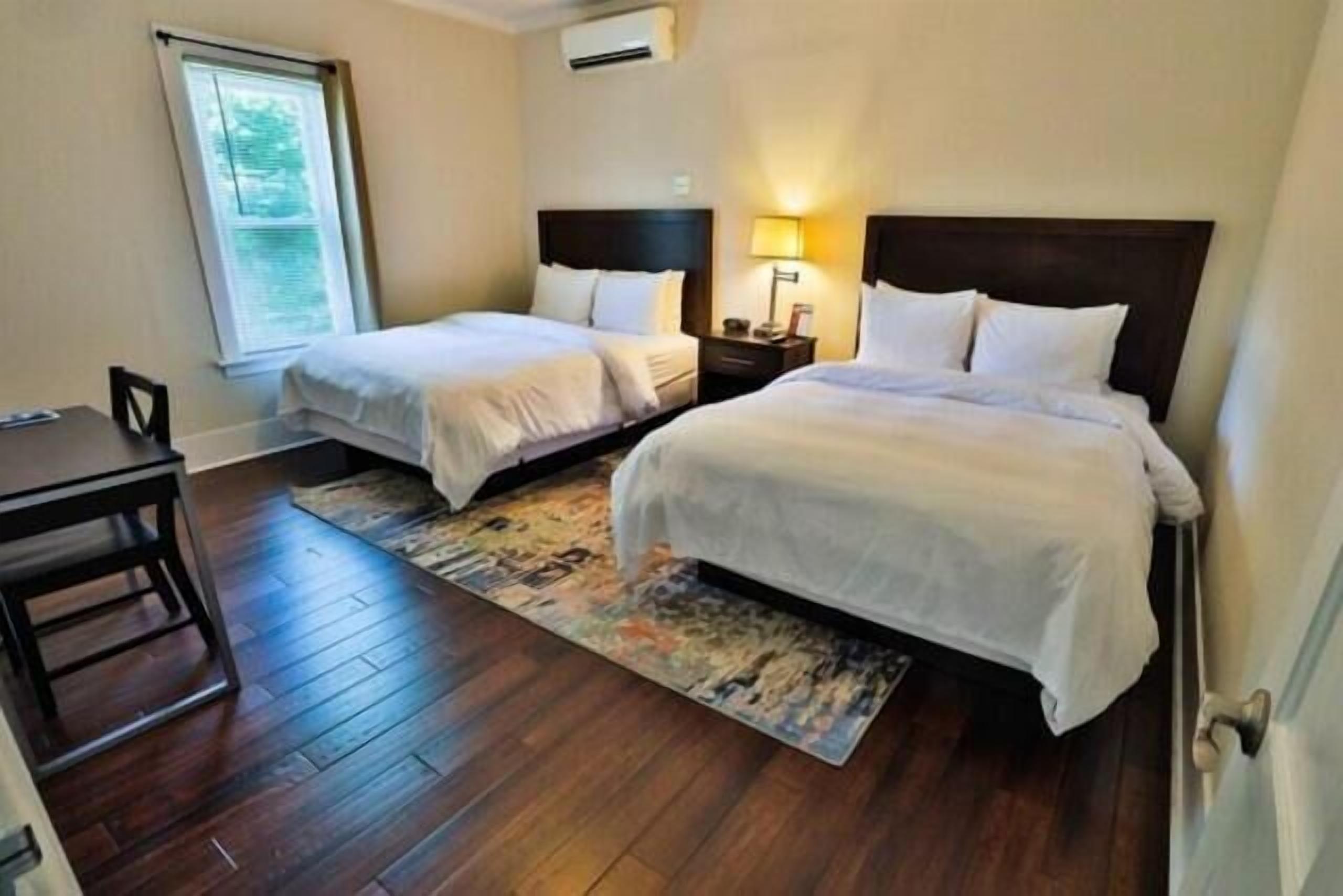 A hotel room with two single beds, a desk, and a chair.