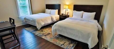 A hotel room with two single beds, a desk, and a chair.