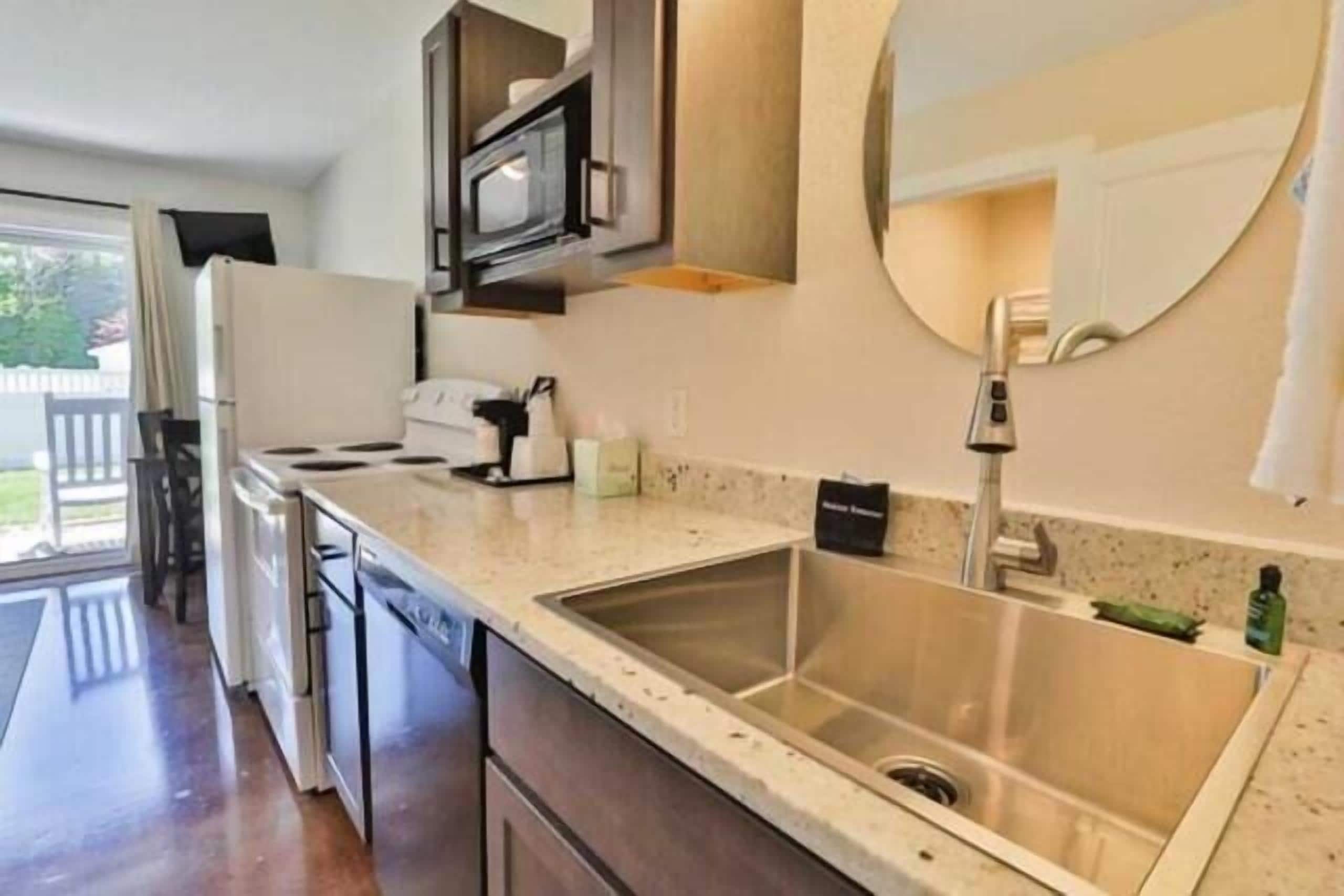 A kitchen with a stainless steel sink, a microwave, and a dishwasher.