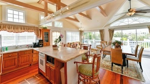 A spacious kitchen with wooden cabinets, a large island, and a dining area with wicker chairs. - Old Colorado Inn (Stuart)