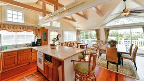 A spacious kitchen with wooden cabinets, a large island, and a dining area with wicker chairs. - Old Colorado Inn (Stuart)