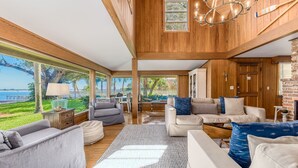 A spacious living area with a large window overlooking a lush garden and a body of water. - Old Colorado Inn (Stuart)
