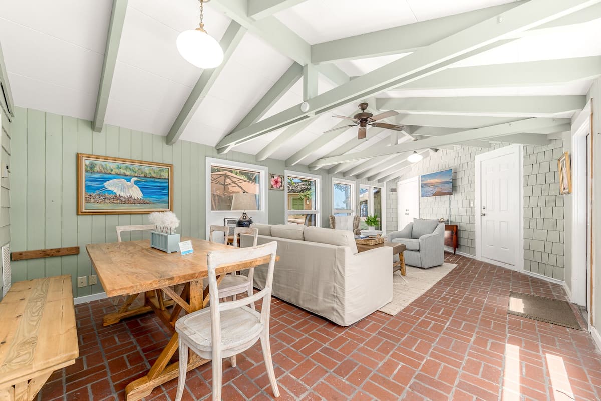 A spacious living area with a wooden table, white sofa, and a ceiling fan.