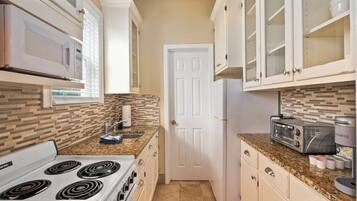 Una cocina con estufa, microondas y tostadora.