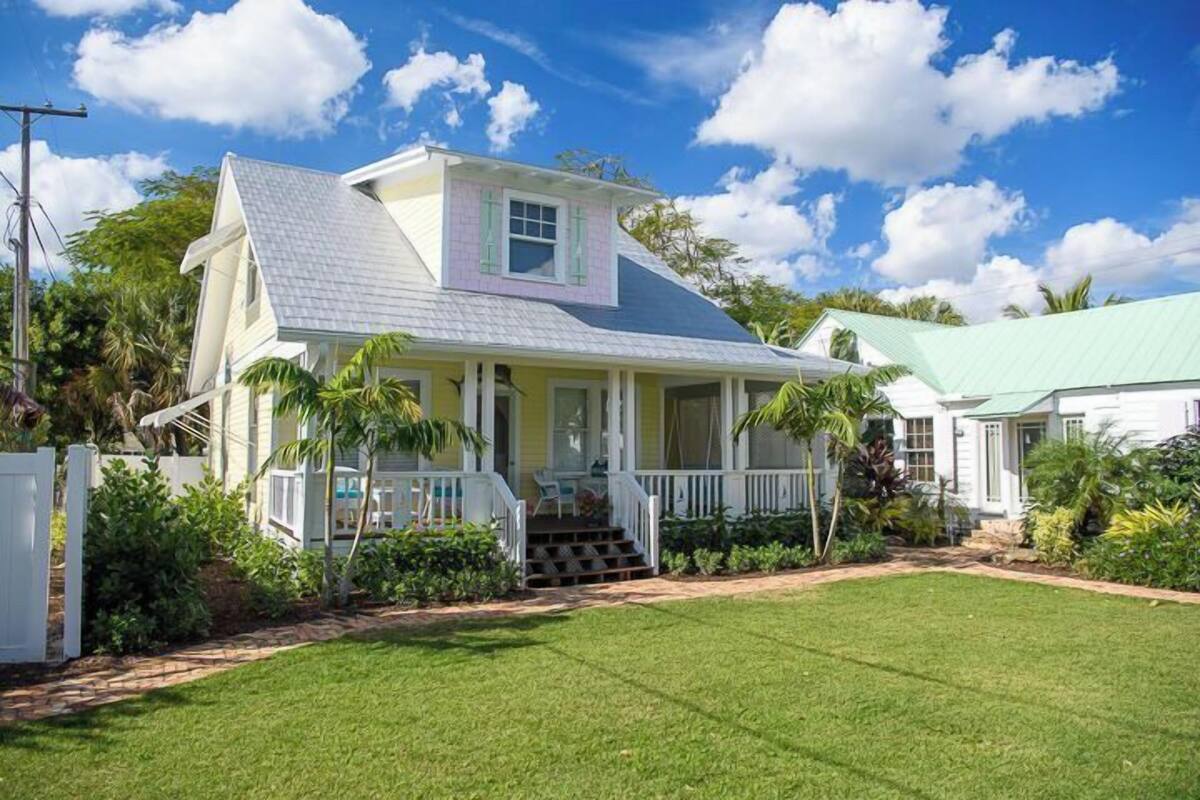 A two-story house with a porch, a small staircase leading to the entrance, and a well-maintained lawn.