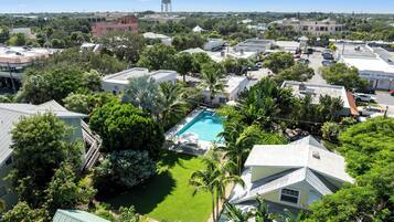 A residential area with a swimming pool surrounded by lush greenery and palm trees.