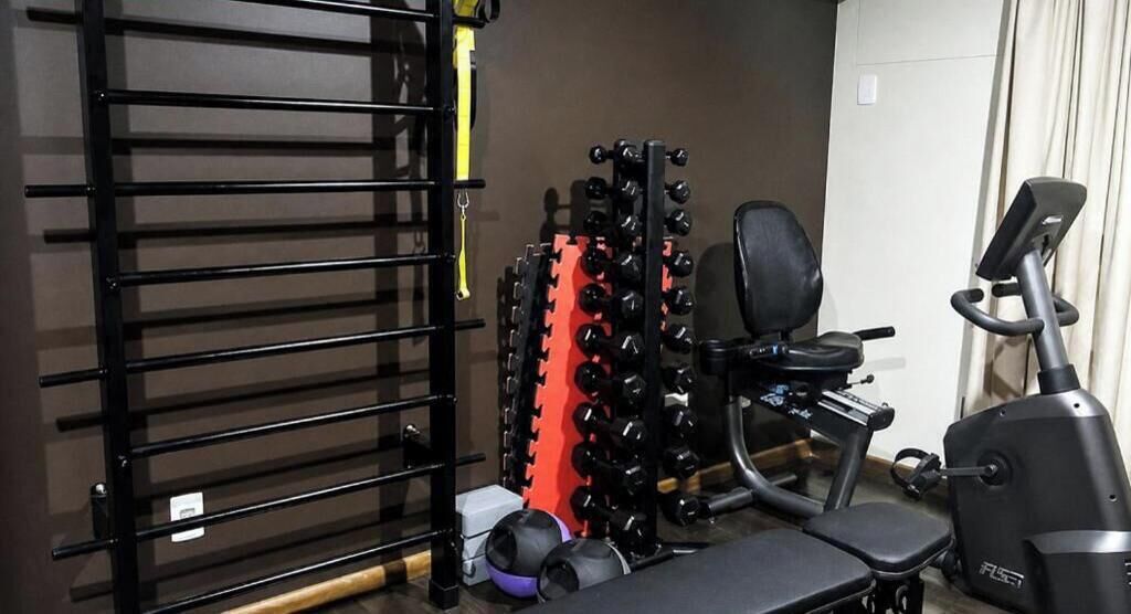 Une salle de sport à domicile équipée d’une barre de traction, d’un support à poids, d’un banc et d’autres appareils d’exercice.