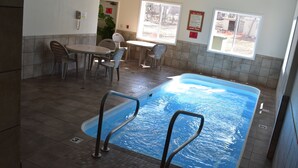 A pool area with a table and chairs, a phone, and a window. - White Pine Lodge (Munising)
