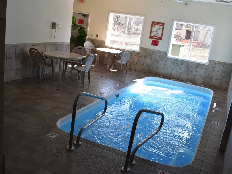 A pool area with a table and chairs, a phone, and a window.
