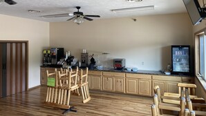 A spacious kitchen with wooden cabinets, a ceiling fan, and a refrigerator. - White Pine Lodge (Munising)