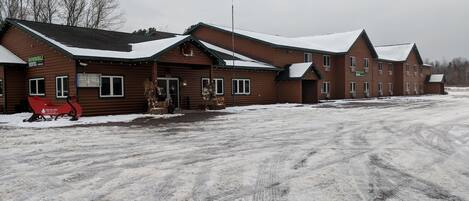 A row of log cabins with snow on the roofs, a sled, and a sign for a showmobile rental.
