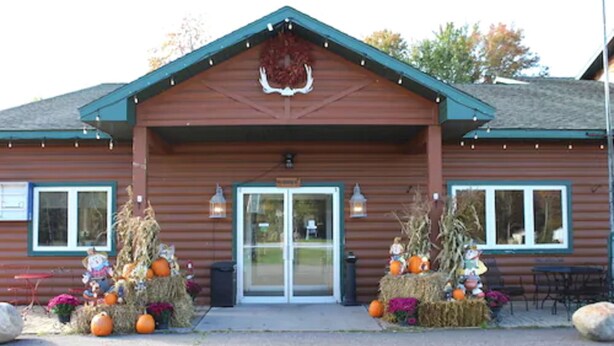A wooden cabin with a front door, two windows on either side, and a wreath above the door. - White Pine Lodge (Munising)