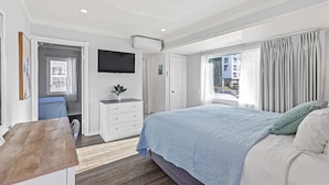 A bedroom with a large bed, a flat-screen TV mounted on the wall, a desk with a chair, and a window with curtains. - Ocean Lodge Santa Monica Beach Hotel (Santa Monica)