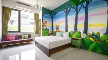 Relax in a serene space with a large bed, vibrant nature-inspired mural, and a cozy sofa.
