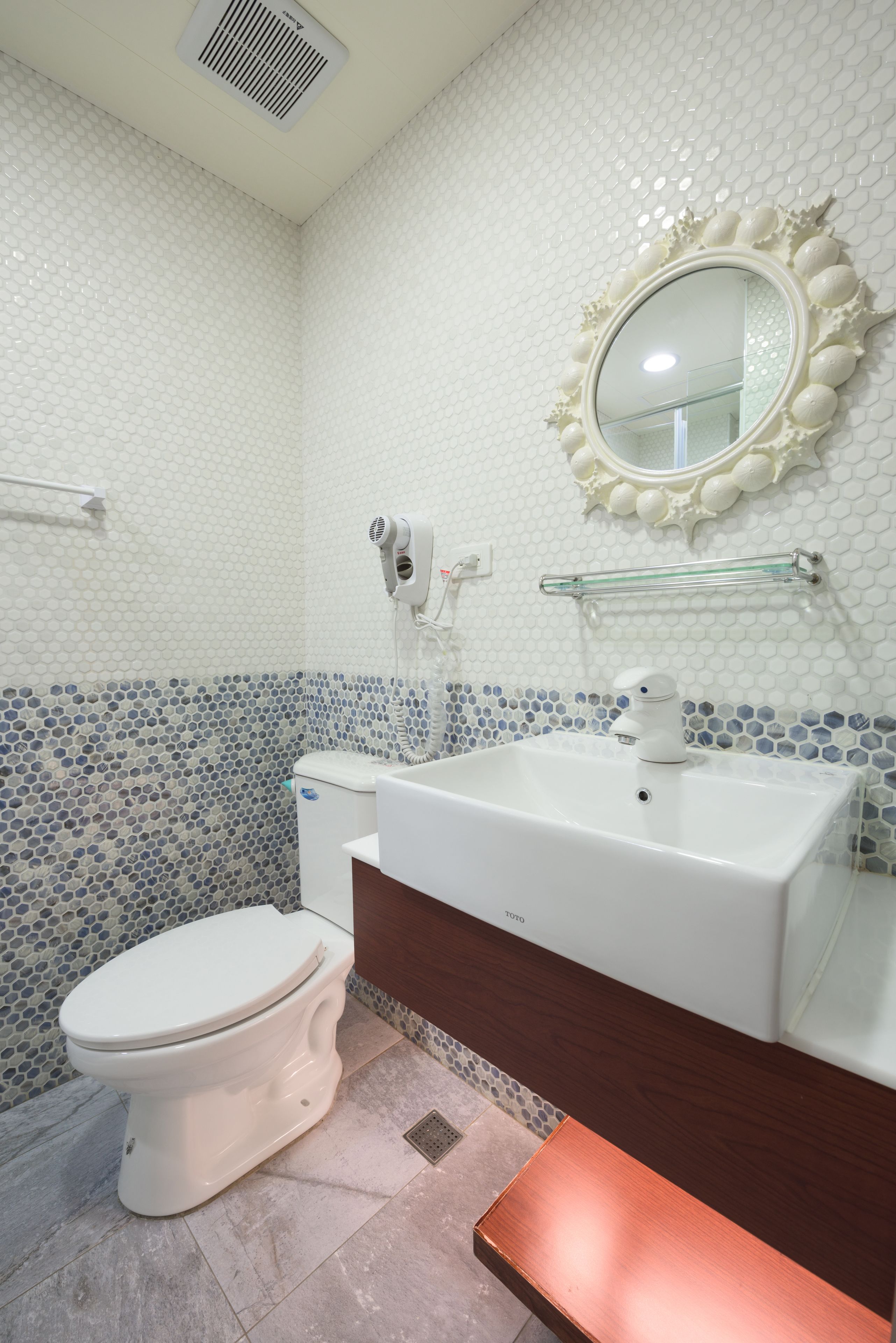 Een badkamer met toilet, wastafel, spiegel en een föhn.