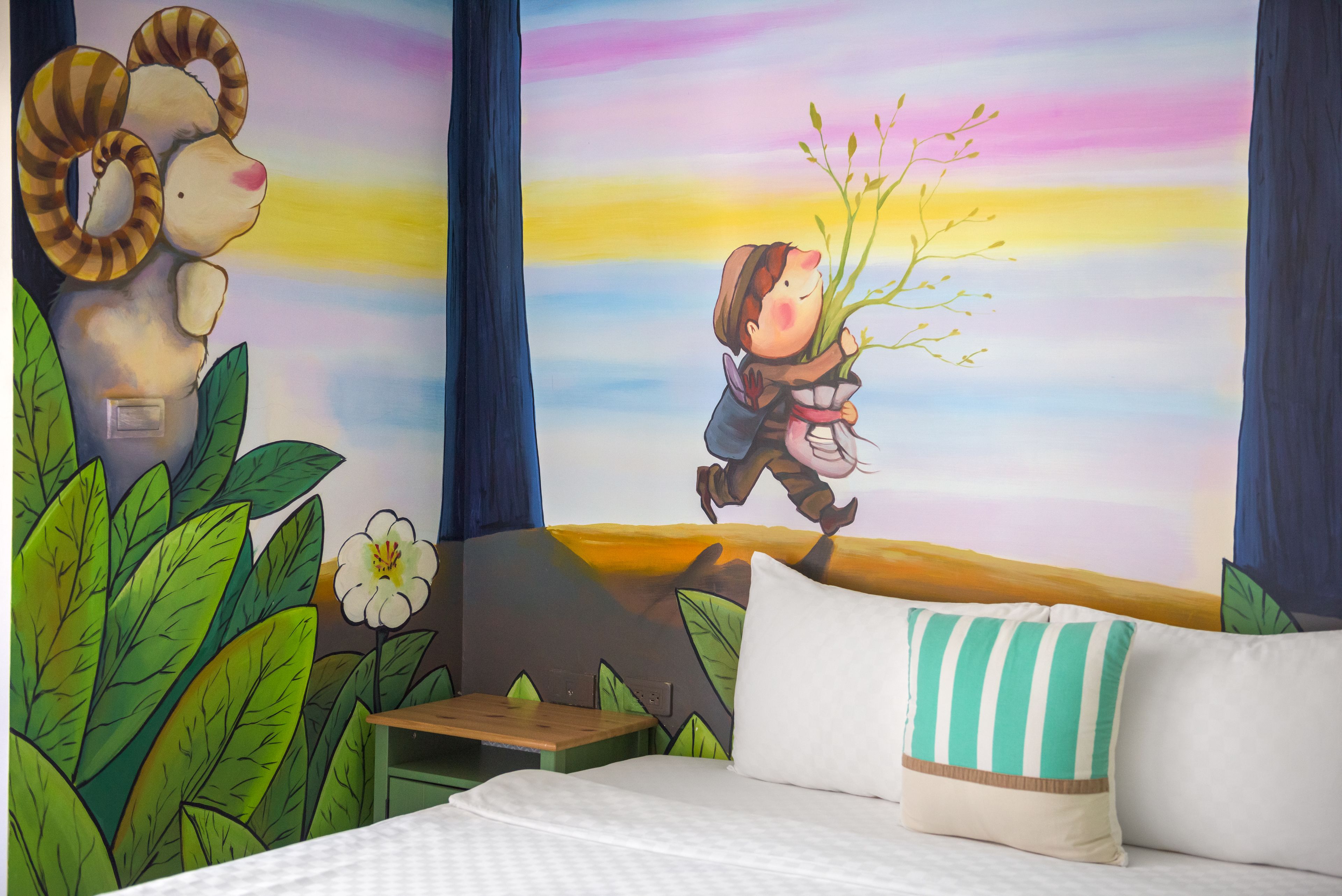Makuuhuone, jonka seinällä on seinämaalaus, jossa poika pitää kädessään kasvia. Huoneessa on myös sänky, yöpöytä ja tyyny.
