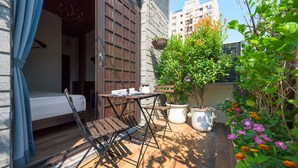 A small, cozy outdoor space with a wooden table and chairs, a potted plant, and a hanging basket. - Luna's House (Kaohsiung)