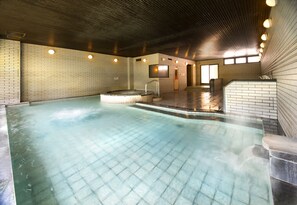 A large indoor swimming pool with a tiled floor, a hot tub, and a staircase leading to a door. - Azumino Hotaka View Hotel (Azumino)