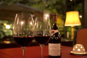 Two wine glasses filled with red wine, a wine bottle, and a table lamp on a table. - Azumino Hotaka View Hotel (Azumino)