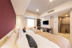 A hotel room with two beds, a TV, a desk, and a small seating area.