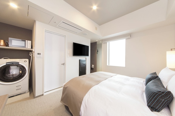 A hotel room with a bed, a washing machine, a television, and a window. - Tokyu Stay Ginza (Tokyo)