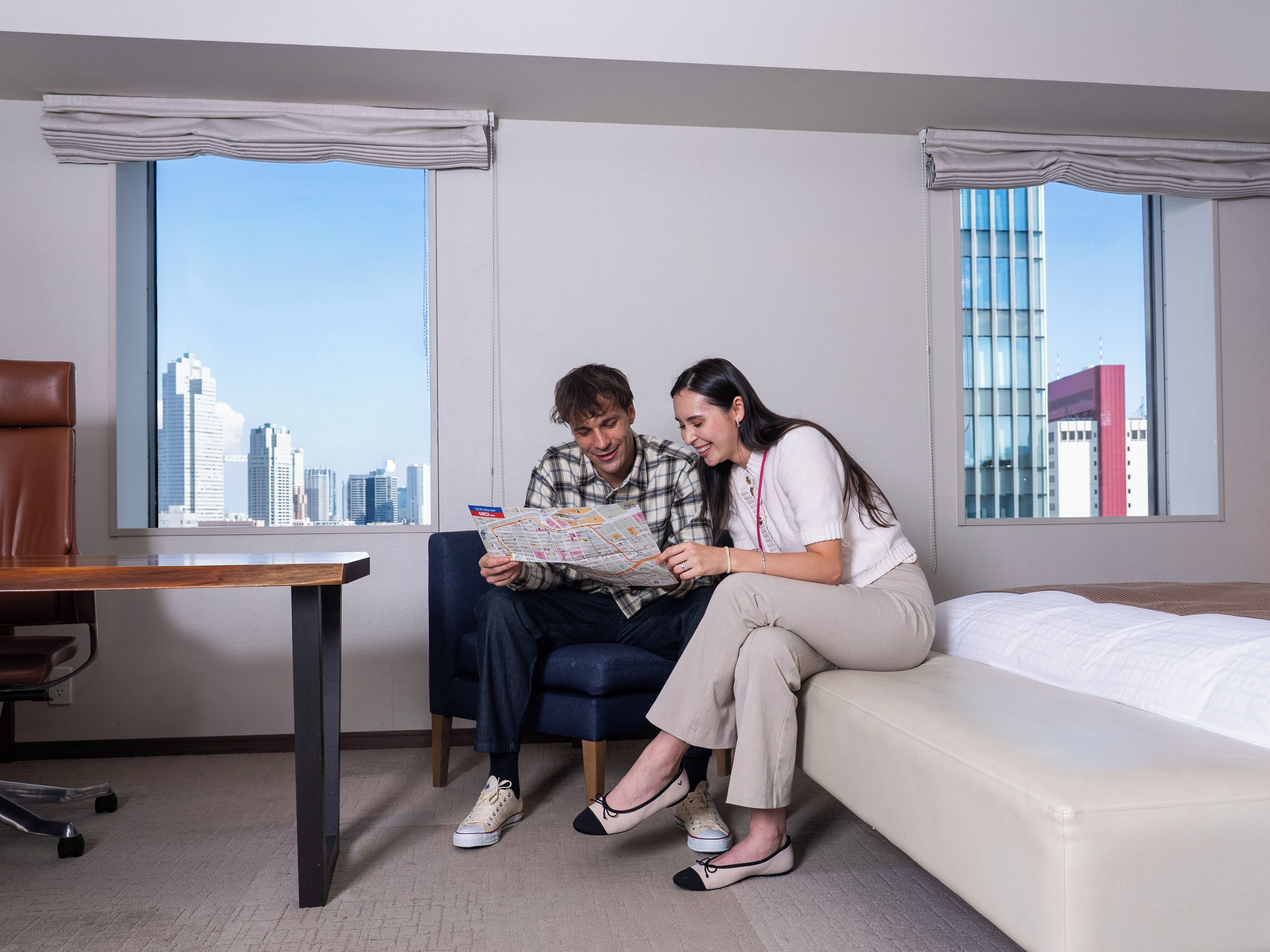 Een hotelkamer met uitzicht over de stad, een bureau en een bank.