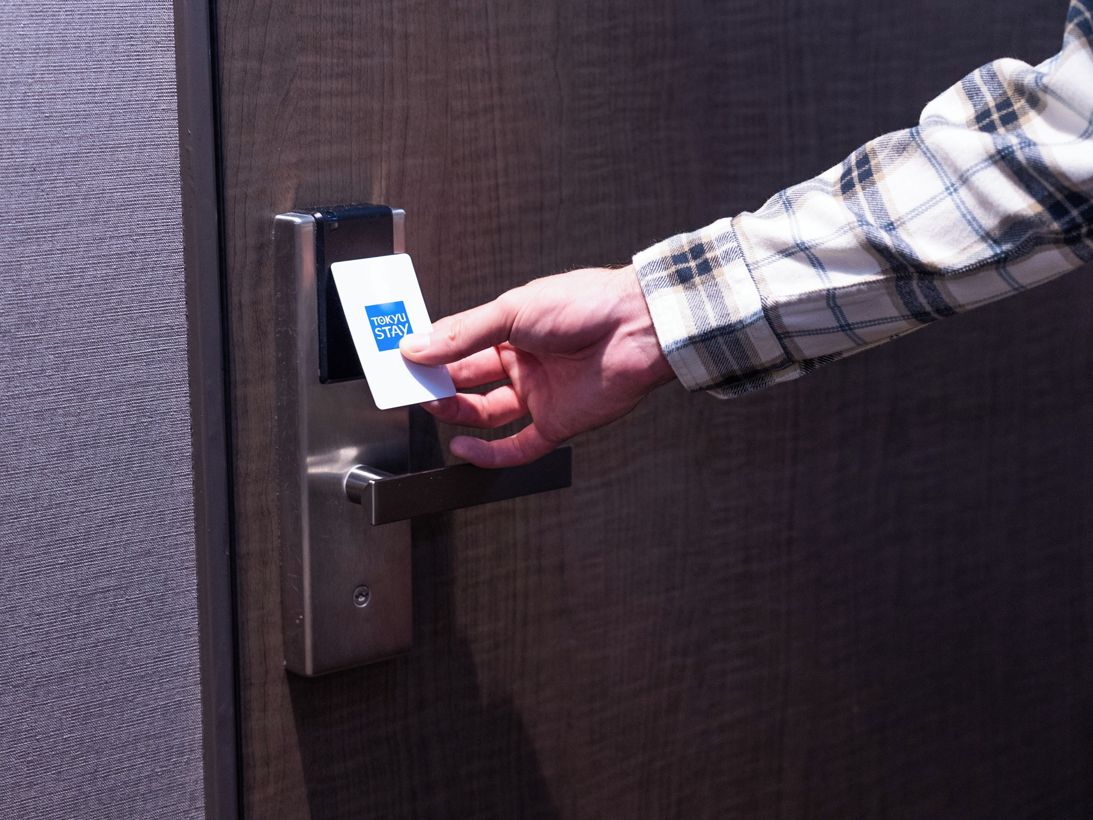A hand inserting a card into a card reader on a door.