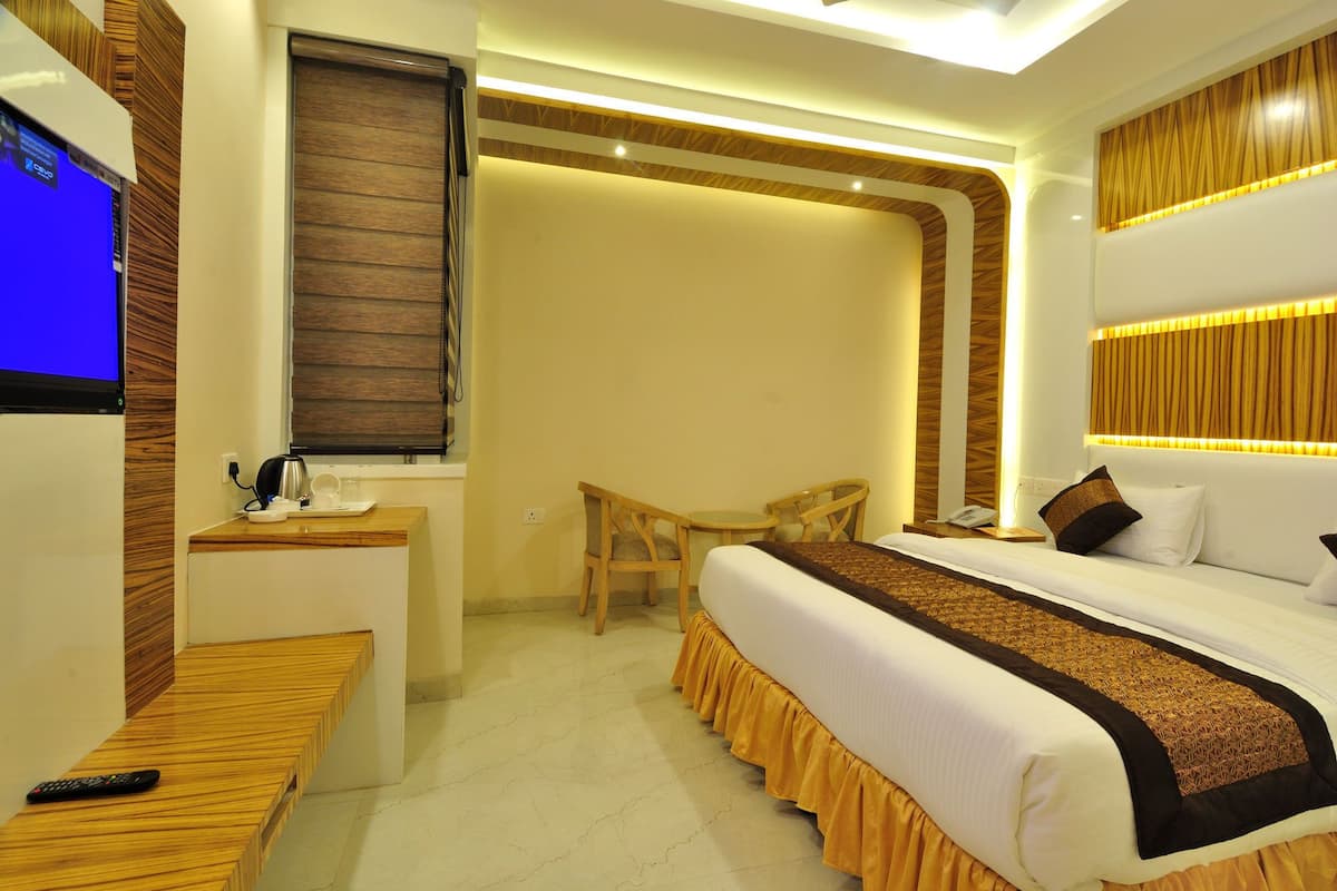 Una habitación de hotel con cama, mesita de noche, silla y televisión.