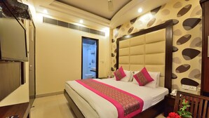A hotel room with a large bed, a bedside table, a TV, and a bathroom door. - Hotel Sonu Dx New Delhi Railway Station (New Delhi)