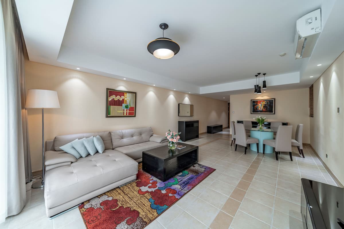 A modern living room with a sofa, coffee table, and a dining area with chairs and a table.